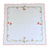 Square white tablecloth with red exterior border, and an interior border of grass, field flowers, and mushrooms.
