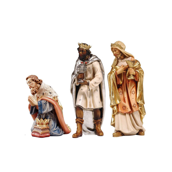 Kneeling King Caspar wears a white-blue gown decorated with fleur-de-lis accents. His cape is terracotta colored with a white ermine cloak, his crown is resting on a stool in front of him, his hands are in prayer. Black standing King Balthazar wears a white gown with a long silver cape and boots. He is holding a chalice with both hands. Standing King Melchior is dressed in a cream and peach gown with golden cape and headscarf, holding his chalice in the left hand, his right hand on his heart.