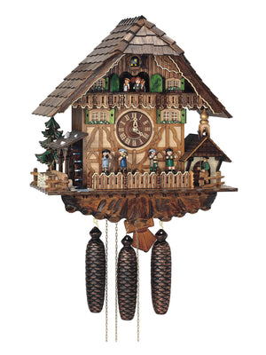 8-Day Schneider Black Forest Chalet Coocoo Clock with music. The half timbered chalet is white with tan and brown accents. A quartet of four oompah band musicians play their instruments behind a fence. A man rings the bell of the bell tower on a mini chapel on the right, and a water wheel spins on the left behind a stone wall where a pile of firewood is neatly stacked. The dancers dance on the balcony on the top floor. The windows have green shutters and the roof has wooden shingles. 