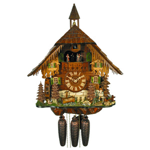 8-Day Chalet August Schwer Black Forest coocoo clock. The clock features a rustic mill with a steeple on the shingled roof. The lower part resembles stone and the upper is made of wood logs. There is a water wheel on the left side with stones and a tree in the corner. The front features more trees with a little fawn lying on the left, jugs, log piles and a water pump and trough. On the right, a boy holds a baby goat, an elder goat beside them, by a water well. Dancers spin on the balcony above the dial. 
