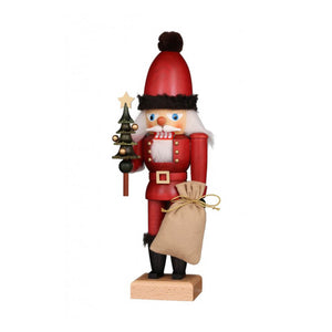 Glazed Santa Claus nutcracker, holding a bag in one hand, and a miniature Christmas tree in the other.