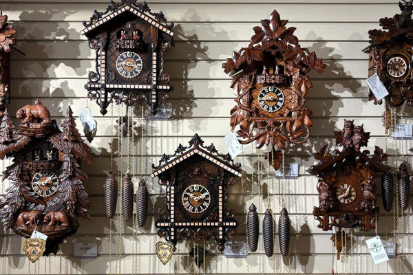 Display of traditional and chalet cuckoo clocks with carved wood details and hanging weights