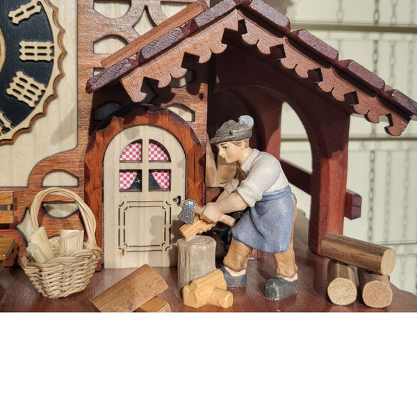 Hand-painted wood chopper figure on an authentic Black Forest chalet cuckoo clock