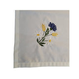 Close-up of cornflower, daisies, and barley bouquet design on linen table cloth