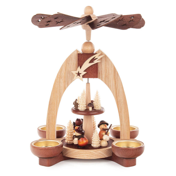 This beautiful, hand carved Christmas pyramid holds a candle on each of the sides of its base to provide gentle lighting on every side when in use. The heat from the candles causes the top propeller in the center of the pyramid to turn. There are trees and woodsmen who are carrying wood and knapsacks on the bottom main platform and smaller trees and mushrooms on the smaller upper platform.