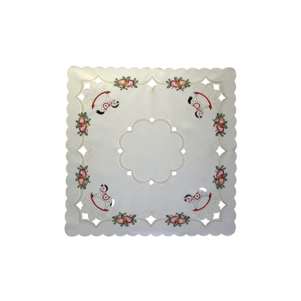 A square cream tablecloth with scalloped edges featuring a floral pattern with rocking horses, crystals, apples, and holly, displayed on a plain background.