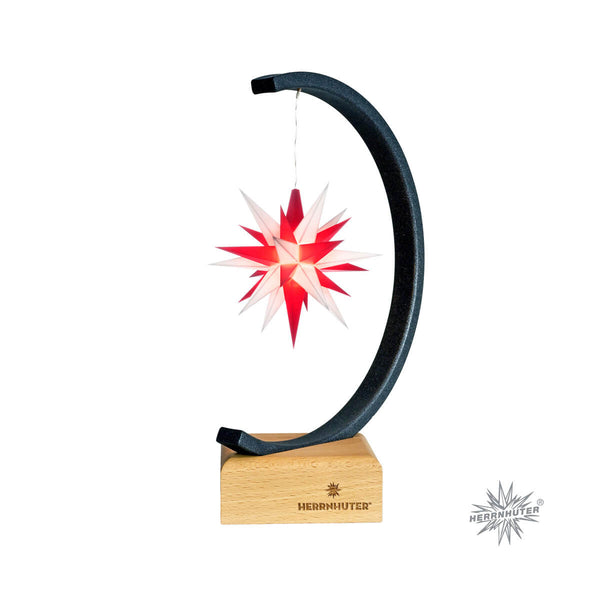 A Moravian Christmas star with a white and red 25-pointed star hanging inside a metallic arch, mounted on a wooden base with a battery holder.
