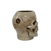 Profile view of ceramic skull beer stein showing bone-white surface, dark gray shading in eye and nose cavities, and detailed tooth structure.
