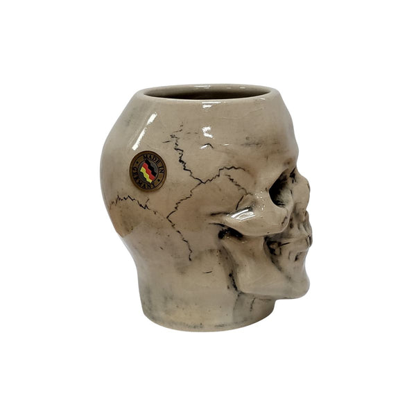 Profile view of ceramic skull beer stein showing bone-white surface, dark gray shading in eye and nose cavities, and detailed tooth structure.