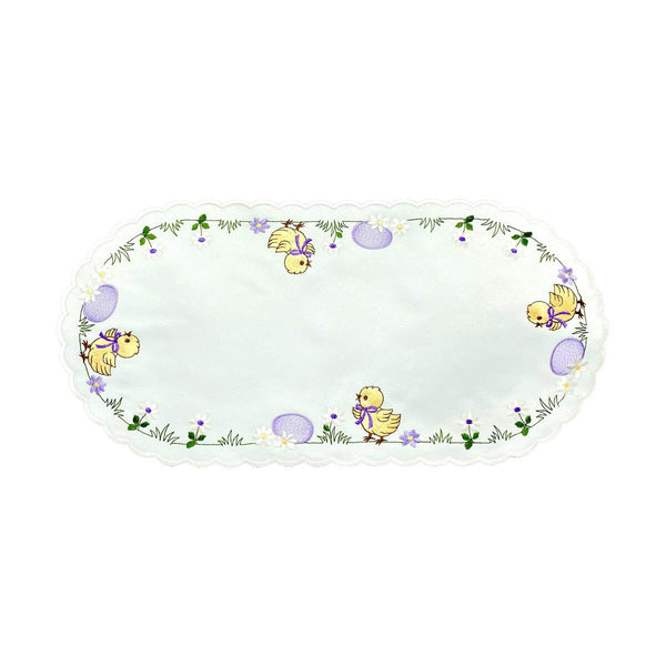 Oval white table runner with scalloped edges, with a border of yellow chicks wearing bows, pink eggs, and a field of daisies.