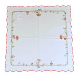Square white tablecloth with red exterior border, and an interior border of grass, field flowers, and mushrooms.