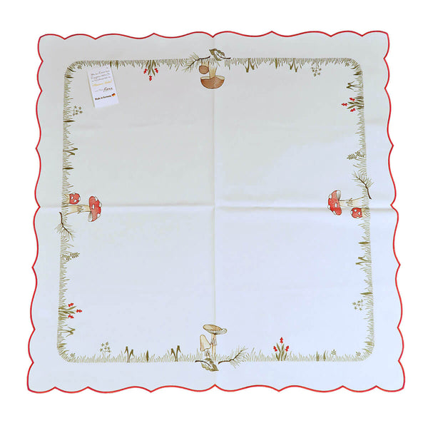 Square white tablecloth with red exterior border, and an interior border of grass, field flowers, and mushrooms.