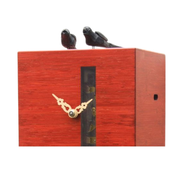 Close-up of DUETT red cuckoo clock showing visible mechanics and carved wooden birds.
