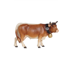 A PEMA Kostner Nativity Cow, featuring a lifelike brown and white design with a bell around its neck. Its pose, looking to the right, brings curiosity and liveliness to your holiday nativity scene