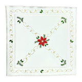 Square white table linen with a red poinsettia in the center, and diagonal designs of golden stitching resembling vines. An outer border follows the same vine looking golden stitching with green leaves.