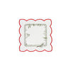 Square white table linen with scalloped edges and a red border, with an interior border design of forest foliage.