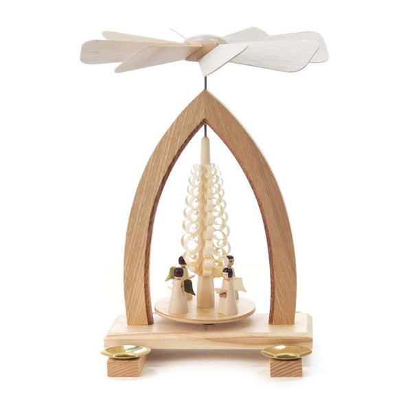 This beautiful Christmas pyramid holds four candles, two on each side. It features a single tier platform under a wooden arch. In the middle of the platform sits an ornately carved wooden tree with meticulously coiled wood shavings, under which four angels dressed in long white robes sing holding their hymnals.