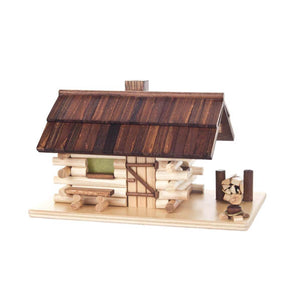 This hand-carved log cabin is made in Germany. The main structure is made of natural wood, the roof is a darker wood tone. There are intricate details like a stack of firewood between two poles, a fireplace, and a bench underneath the cabin window. There main structure lifts off the base and there is a holder for the incense cone inside. When the incense is lit, the smoke comes out the chimney.