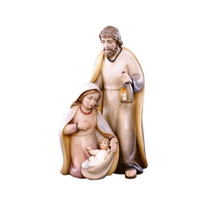 Sculpted wooden Holy Family figurines for Artis Nativity set. Baby Jesus is cradled in swaddling by Mary as she looks down upon him. Joseph stands behind them, holding a lighted lantern in his hand.