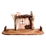 Stable display for Artis Nativity set. Includes a weathered stable wall with roof, surrounded by trees and wooden fences.