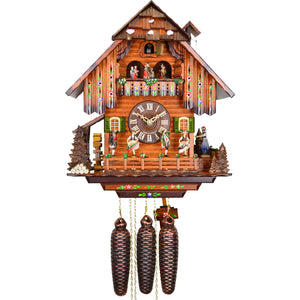 8-Day Chalet August Schwer Black Forest coocoo clock. The solid wooden clock features a waterwheel under an overhang to the left of the house, A green tree with a pile of logs decorates the left corner. Four dancers dance on a fenced platform decorated with flowers along the width of the house. On the right, a woman in Black Forest clothes is pulling a cord, ringing the bell on the right side of the roof. Above the dial, smaller dancers spin to the music. Above the cuckoo comes out from behind the door. 