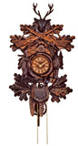 1-Day Schneider Traditional Hunting Coocoo clock. The clock has different shades of brown. A hunter’s horn is encircled around the dial. A pheasant and a rabbit decorate the sides, a hunting bag the bottom. The cuckoo bird comes out behind the door above the dial and there are two rifles crossed above the cuckoo door. A stag head juts out above the rifles. The side of the clock box is decorated with leaves.