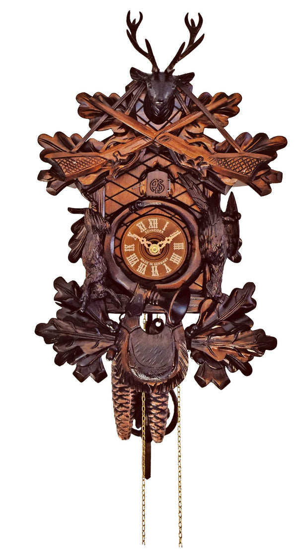 1-Day Schneider Traditional Hunting Coocoo clock. The clock has different shades of brown. A hunter’s horn is encircled around the dial. A pheasant and a rabbit decorate the sides, a hunting bag the bottom. The cuckoo bird comes out behind the door above the dial and there are two rifles crossed above the cuckoo door. A stag head juts out above the rifles. The side of the clock box is decorated with leaves.