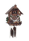 1-Day Schneider Chalet Black Forest Coocoo clock. The face of the clock is white and dark wood paneling up top. There are two evergreen trees on each side. On the right, a man is sitting next to a fence at a table drinking beer with his dog wearing a small keg on the collar. A waterwheel is spinning and a carved wood fountain with trough is decorating the left. Dancers on top of the balcony spin to the music, above them the cuckoo door. The chimney sweep pops up and down when the bird calls.