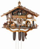 8-Day Schneider Black Forest Chalet Coocoo clock with music. The lower level of the house is painted white, the upper level has wood paneling. Next to the dial in the middle sits a beer drinker on a bench. A waitress carrying beer steins comes out of the door to serve another Bavarian beergarden guest sitting on the right under the Biergarten sign. A horse drawn beer wagon with kegs arrives on the left. Dancers spin on the wide balcony above and the wood-shingles roof has a pretty belltower.