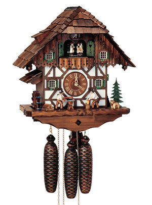 8-Day Schneider Chalet coocoo clock with music. The half-timbered chalet is white with dark wood on the upper half. Next to a green fir tree a little dog with a keg around his neck watches a man chopping wood to the right of the dial. Another wood chopper saws wood, a pile of firewood is stacked behind him. There is a water wheel on the left underneath a little overhang, The dancers spin on the balcony. The cuckoo comes out behind his door above the dancers. The roof is made of wooden shingles.