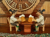 Two Bavarian men in Lederhosen drinking Beer under the dial on Schneider Black Forest Cuckoo Clock