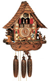 8-Day Black Forest Chalet Schneider coocoo clock with music. The chalet is white with curved brown timbers. A green fir tree sits on each side. On the left, a water well sits next to a water wheel, the little brook is lined with stones. On the right, there is a stag behind a fence, and a boy and a girl are seesawing on a teeter-totter in the middle underneath the dial. The two windows have red shutters and flower boxes underneath. Dancers spin above an ornate balcony. The roof has shingles.