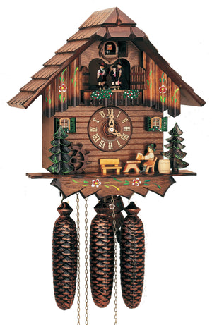 8-Day Black Forest Chalet Schneider coocoo clock with music. The chalet resembles a log cabin. An evergreen tree with a waterwheel sits on the left, a light colored natural bench in the middle and a man sitting at a table drinking beer from a stein on the right next to a natural colored barrel and a green tree on the right. The windows next to the dial have green shutters and floral window boxes underneath. The balcony up top is decorated with flowers and dancers spin above. The roof is made of shingles.