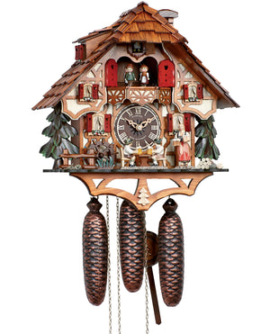 8-Day Black Forest Chalet Schneider coocoo clock with music. The chalet is white with curved brown timbers. A green fir tree sits on each side. A water wheel spins on the left, two men are sitting at a table drinking beer underneath the dial and a waitress is carrying more beer steins on the right. A pile of wood and stones sit on the right corner. The windows have red shutters and flower boxes underneath. Dancers spin above an ornate balcony. The roof has shingles.