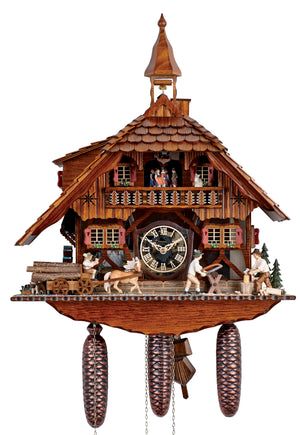 8-Day Black Forest Chalet coocoo clock with music. The dark wooden clock shows a water wheel, a horse drawn carriage with logs, a man sawing wood on a sawhorse and a man chopping wood. Two green trees sit on the right. Two double windows on each side of the clear see-through dial have red shutters and flower boxes. The dancers spin on a wide balcony with tree themed railing. The roof has shingles, a dormer window, a chimney, and a large bell tower.
