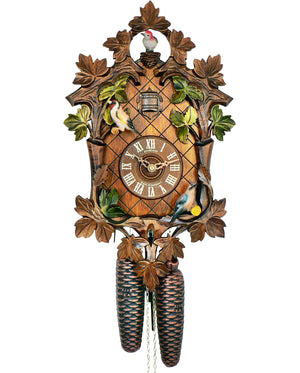 8-Day Black Forest Traditional coocoo clock. The front face has diamond shaped gridlines. Carved brown wooden leaves and smaller green ivy leaves decorate the edge of the clock. One colorful bird sits on the lower right corner of the clock, another one on the left upper corner. The third colorful bird looks out a little carved nest at the very top of the clock and is surrounded by carved ivy leaves.