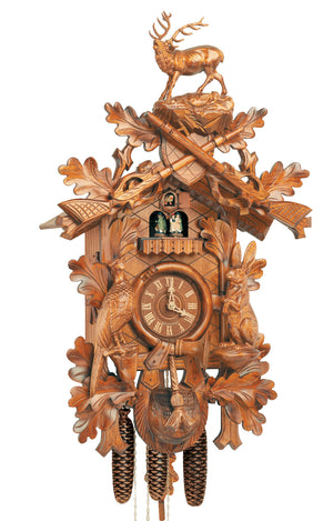 8-Day Black Forest Traditional coocoo clock. The solid wood traditional hunter style clock features a rabbit on his hind legs on the right edge of the clock and a pheasant looking up on the left edge. The cross-hatched front is decorated with oak leaves. A hunter’s pouch is featured at the bottom. The dial is encircled by a horn. Dancers spin on a balcony underneath the cuckoo bird. The roaring stag with large antlers stands above crossed rifles at the top of the clock.