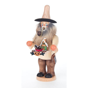 The classic German-made Dregeno Smoker is crafted from natural wood and intricately detailed. The smoker is holding a tray with a gingerbread house and gingerbread cookies. He has a long beard, wears a natural-colored pointy wooden hat with a wide brim and enjoys his pipe.  Perfect for the winter season!