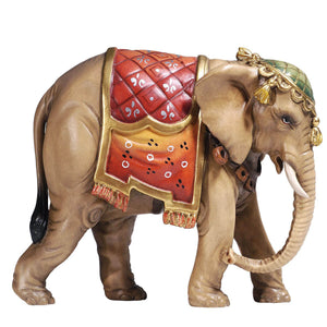 Capture the beauty of the holidays with this unique PEMA Kostner Nativity - Elephant. Hand-carved out of wood and hand-painted, this detailed elephant figurine wears a red blanket, adorned with traditional decorations and a golden, fringed edge, and a tasseled headdress. Bring festive joy to any room with this eye-catching holiday decor!