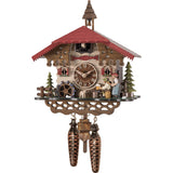 This Engstler Cuckoo Clock is a stunning timepiece crafted in the traditional style of the Black Forest of Germany. Featuring a quartz movement and hand-carved and hand-painted details of a man sitting at a table drinking beer, being threatened by a woman holding a rolling pin behind him. A water wheel, pine trees a water trough complement the idyllic Chalet scene. The cuckoo bird comes out from his door underneath the red roof featuring a bell tower. 