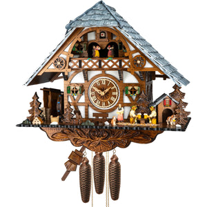 Image of Engstler 8-Day Cuckoo Clock depicting a white timbered chalet facade with a distinctive grey roof. Two beer drinkers sit at a table while a waitress serves drinks, accompanied by two St. Bernard dogs. A waterwheel and woodshed are on the left, and a wooden doghouse on the right. Dancers spin on the balcony, while ornate carvings adorn the bottom of the clock.