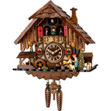 This Engstler Cuckoo Clock is a stunning timepiece crafted in the traditional style of the Black Forest of Germany. It features a battery-driven movement and hand-carved and hand-painted details of a man sitting at a table drinking beer, being threatened by a woman behind him holding a rolling pin. A waterwheel, pine trees, a water trough complement the scene. The dancers twirl on the balcony, above them the cuckoo comes out behind his door. The shingled roof features a chimney.