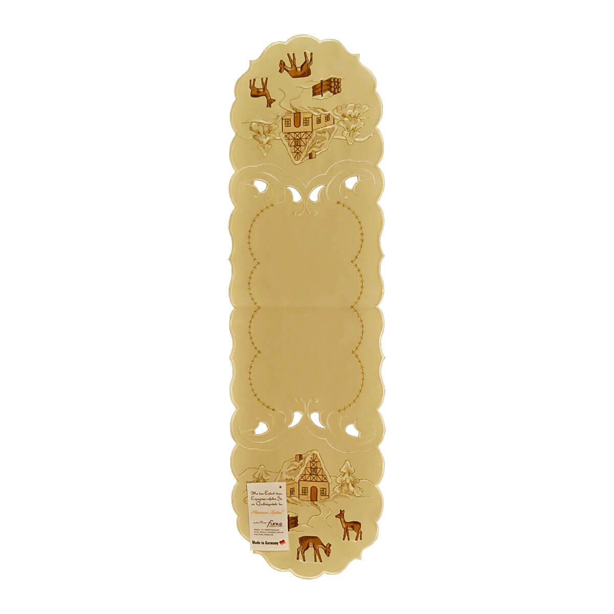 Cream color table runner, with a wavy stitching design in the center, and on either end there are cutouts and a scene of a snowy chalet in the forest, surrounded by deer.