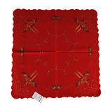 Square red tablecloth, with a curved octagonal gold threading design in the center. A border of lighted candles with holly branches in each corner, and Christmas bells at the base.