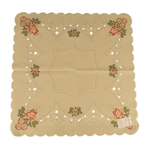 Square cream color tablecloth, with scalloped edges, and cutouts along the border, and a border of Christmas ornaments and lighted candles with holly.