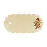 White table runner with scalloped edges. With a diamond shaped cutout on one side, and a bouquet of fall blossoms on the other.