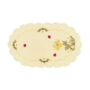 White table runner with scalloped edges, and a large bundle of primrose and daisies at the one side, with an interior border of ladybugs and daisies.