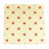 Square white tablecloth with repeating crosshatch design of red poinsettias with leaves.