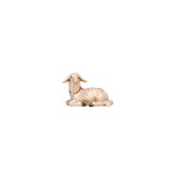 The white lamb has its legs tucked under and is looking left. The lamb is wearing a collar with a bell.