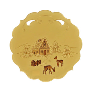 Round cream color table linen with scalloped edges and cutouts, and a design of a snow covered chalet and forest with deer and a bundle of wood.